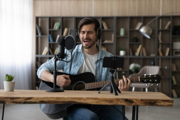 istock Happy young inspired man playing guitar, recording own song. 1329762964
