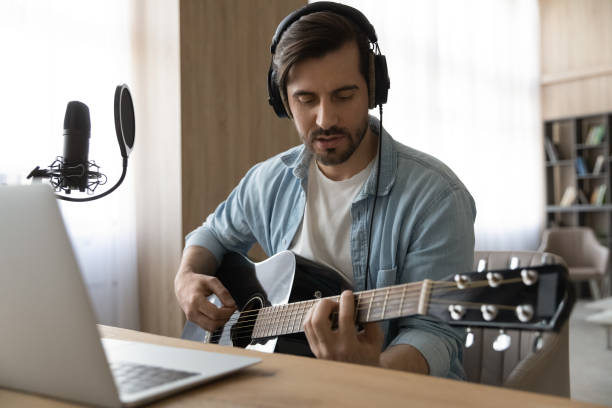 istock Focused young man playing guitar, studying on online courses. 1329762968