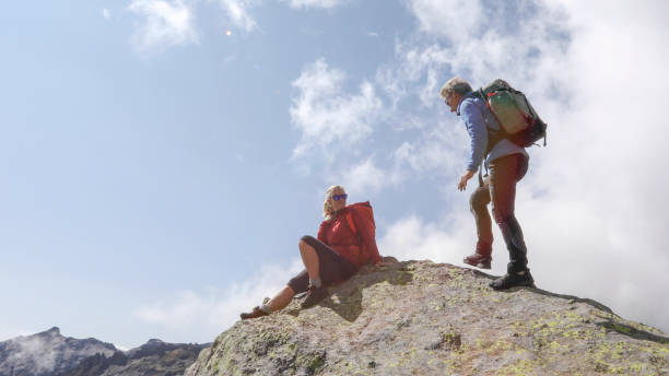 istock Mature hiking couple relax on sunny mountain ridge 1329764091