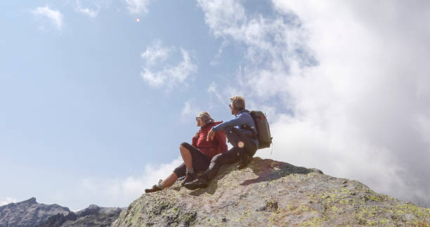 istock Mature hiking couple relax on sunny mountain ridge 1329764098