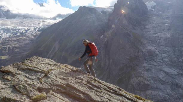 istock Female hiker scrambles up mountain ridge 1329764100