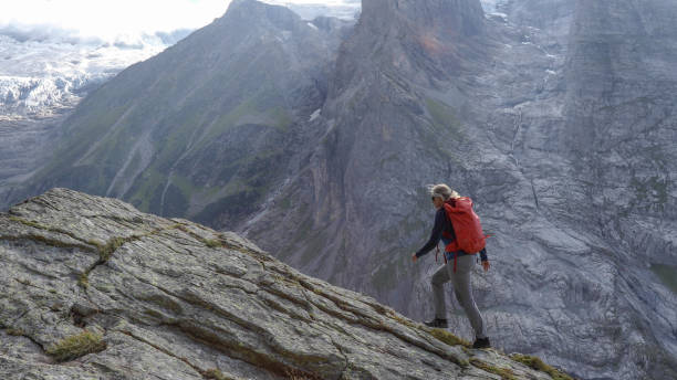 istock Female hiker scrambles up mountain ridge 1329764132