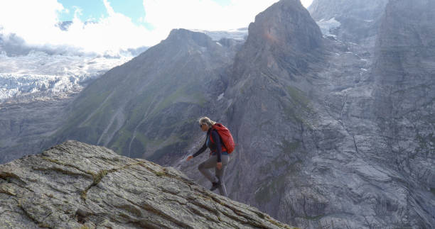 istock Female hiker scrambles up mountain ridge 1329764135
