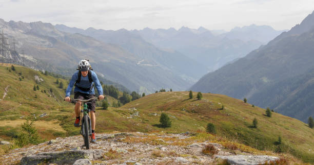 istock Mountain biker rides up alpine mountain ridge 1329764170