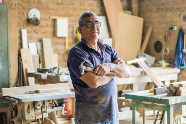 istock Elderly carpenter posing with crossed arms in his workshop. 1329772015