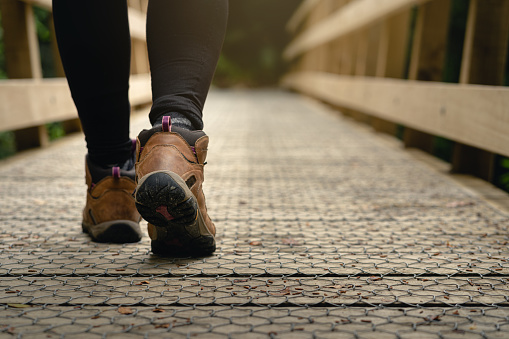 Hiking shoes of a woman walking on wooden bridge. Copy Space on outdoor background.