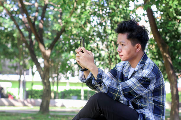istock Asian Young Men using a smartphone playing games in the park 1329784161
