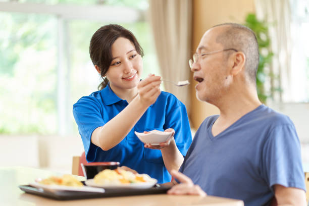 un cuidador que ayuda a los ancianos con las comidas - atención residencial fotografías e imágenes de stock