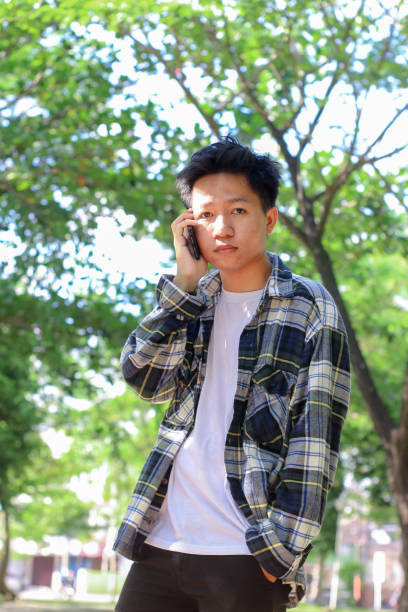 istock Asian young men talking on a phone at the park 1329785891