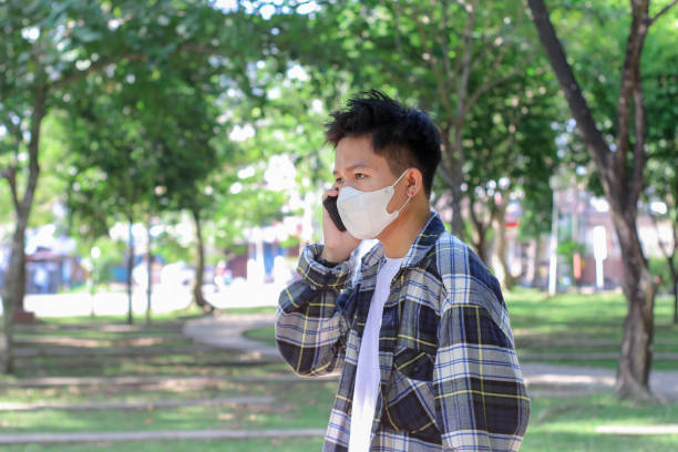 istock Asian young men talking on a phone at the park 1329785974