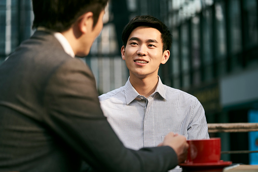 two asian corporate businesspeople discussing business at a outdoor coffee shop