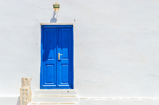 White architecture, blue door and pink flowers. Santorini island, Greece.