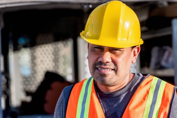 istock Smiling hispanic construction worker wearing a work helmet looking at the camera 1329796062