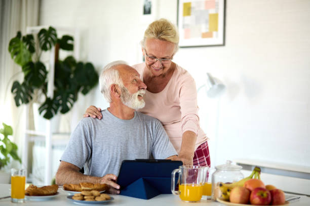 istock Embraced senior couple using tablet during breakfast at home 1329798644