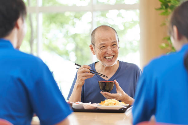 anziani che si divertono a mangiare in una struttura di assistenza a lungo termine - nursing home senior adult group of people home caregiver foto e immagini stock