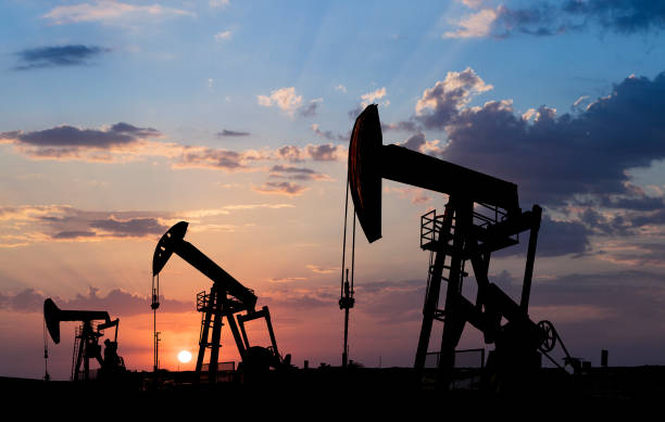 istock Oil pumpjacks in silhouette at sunset 1329800268