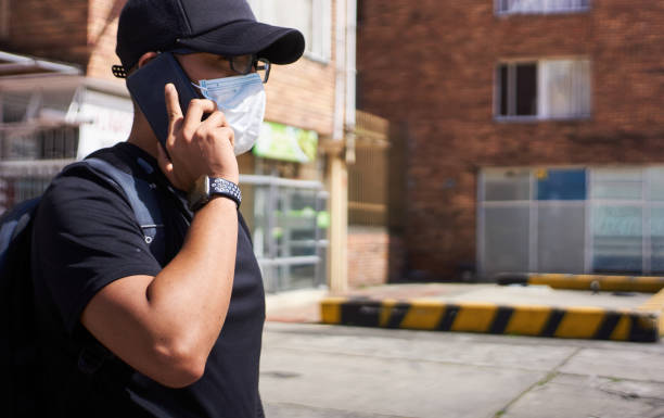 istock a man at noon talking on a cell phone with a mask 1329800403