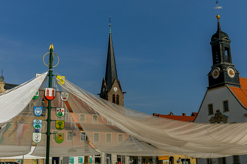 church tower, town hall in the background, in front the market square of a German city with heraldic shields