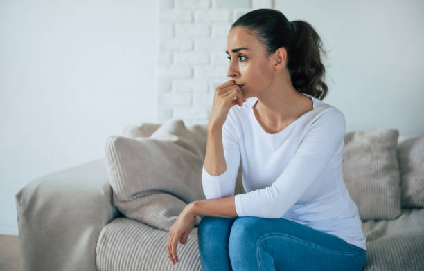 Sad woman in deep depression is sitting on the couch and crying and thinking about the bad thing stock photo