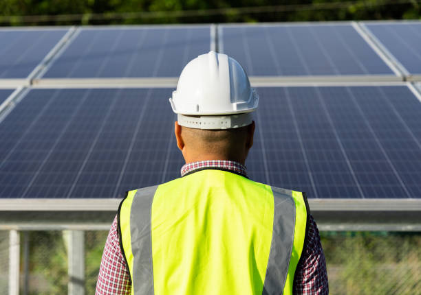 istock Young asian electrical engineer standing in front of Solar cell panels farm. He checking and installing. Solar generator power concept. 1329812438