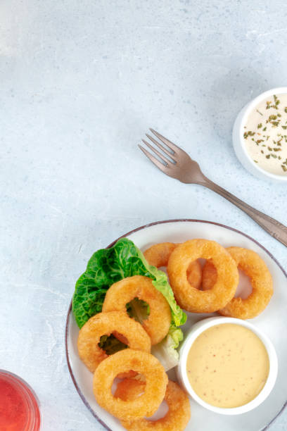 squid rings. delicious calamari with a dip and a green salad leaf - tartar sauce imagens e fotografias de stock