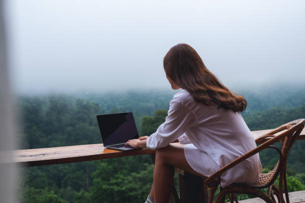 istock a woman using and working on laptop computer while sitting on balcony with a beautiful nature view on foggy day 1329814631