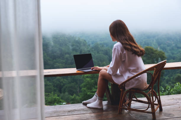 istock a woman using and working on laptop computer while sitting on balcony with a beautiful nature view on foggy day 1329814676