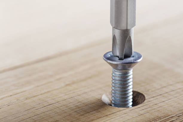 istock Screwdriver screw bolt in wooden oak plank. Spanner, bolt, screw and nuts. 1329816919