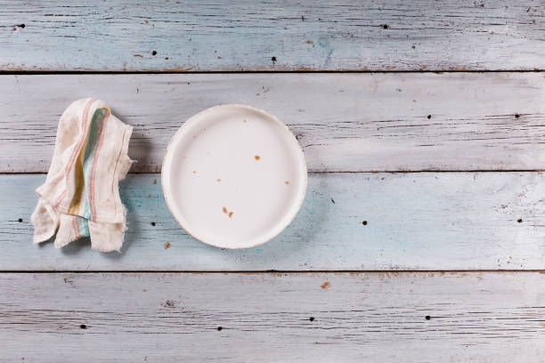 istock Empty white dish and napkin on blue wooden table 1329819910