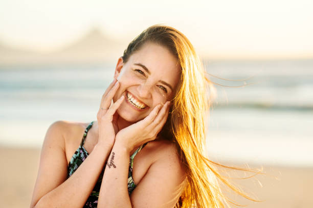 istock Laughing young woman standing on a sandy beach at sunset 1329822658