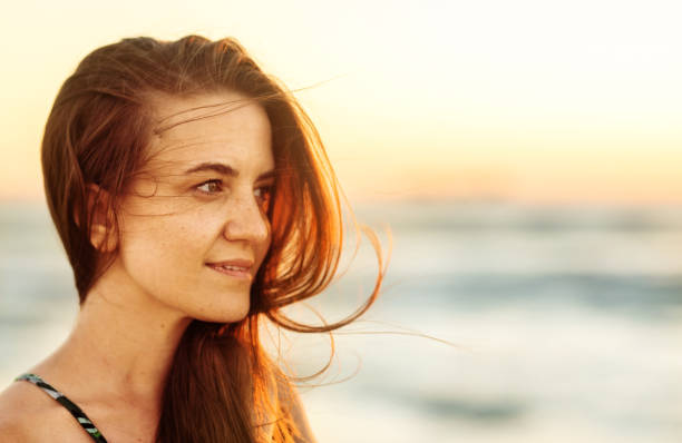 istock Smiling young woman looking at the ocean view at sunset 1329822700