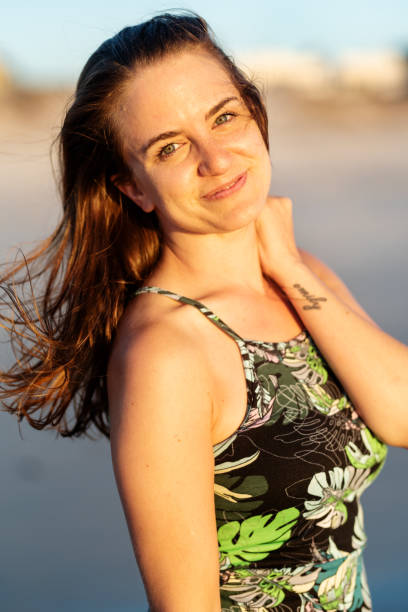 istock Young woman smiling on a sandy beach at sunset 1329822706