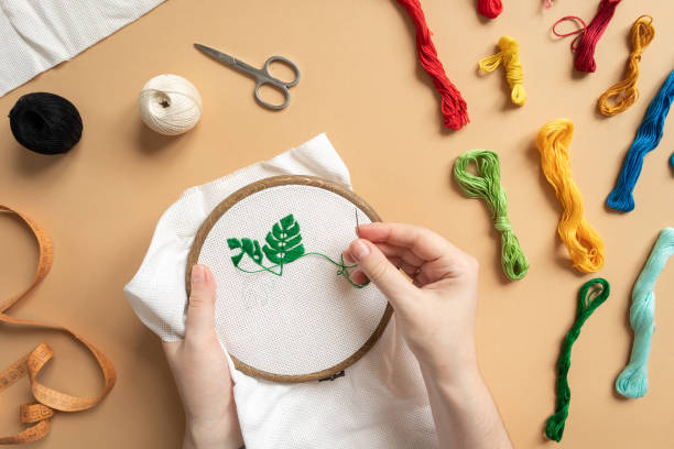 Embroidery in process top view Embroidery in process Embroidery in process top view. Workshop, needlework and colorful knitting. Female hands with needle and thread. Stitching workshop.top view. High quality photo needlecraft product stock pictures, royalty-free photos & images