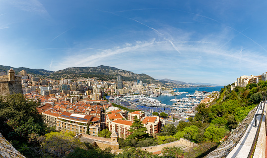 April 30, 2023: This photo shows the glamorous and luxurious principality of Monaco, nestled on the stunning French Riviera. The image captures a panoramic view of the cityscape, featuring the towering hillside, opulent architecture, and the Mediterranean Sea. The photo is also adorned with the yachts moored in the harbor.