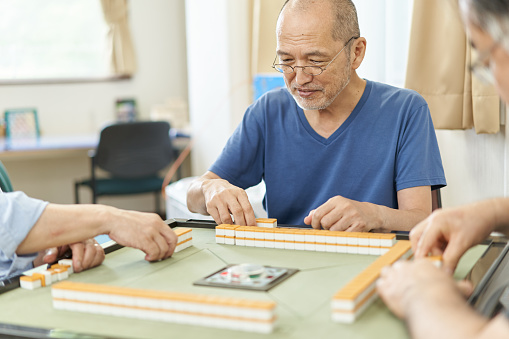Elderly people playing mahjong in the recreation room of a long-term care facility