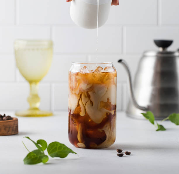 istock Cream is poured into cold black coffee with ice cubes. Coldbrew. Summer drinks. 1329825196
