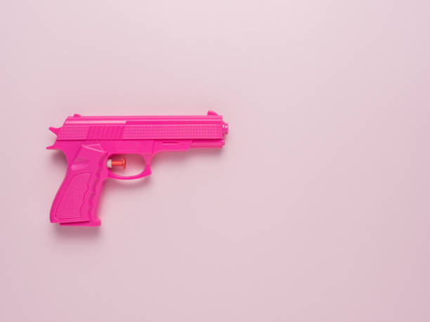 istock Pink handgun on pink pastel background. Minimal flat lay concept. 1329826437