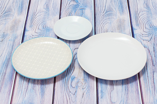 White porcelain saucer and plates on the wooden background. Top view.