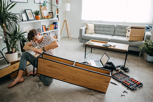 Hombre en un nuevo hogar que ensambla muebles para autoensamblaje photo