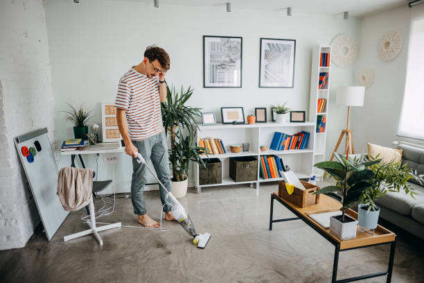 istock Man cleaning house with wireless vacuum cleaner 1329828177