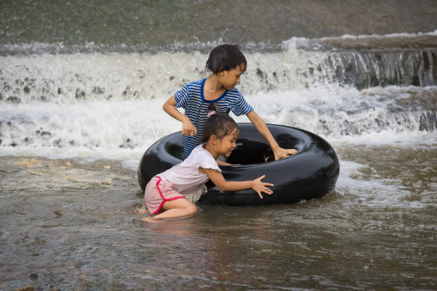 un enfant joue et est resté sur un pneu flottant dans l’eau filmé à chiang mai, en thaïlande. - water sport family inner tube sport photos et images de collection