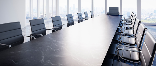 Large conference table with chairs in a meeting room in the high-rise office building, view to the skyline