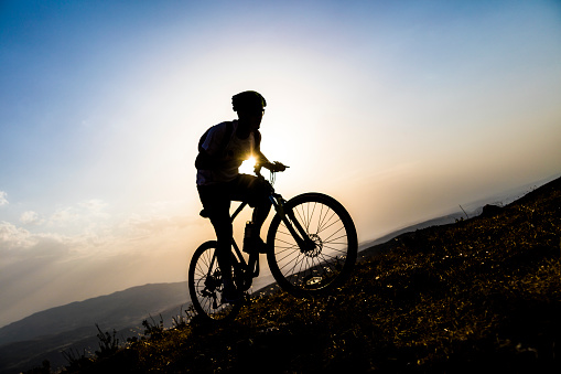 Biker on mountain bike adventure against sunst