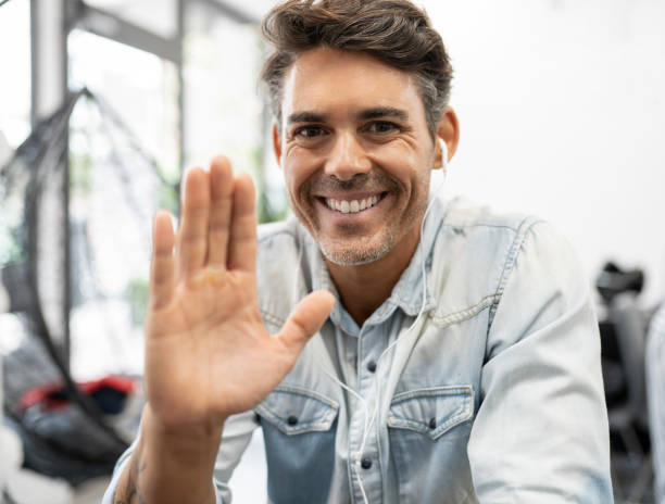 istock handsome man with headphones and looking at computer video call, wave with his hand 1329835864