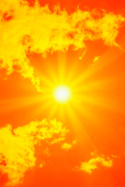 Bright sun with beautiful beams in the sky with some clouds. Toned in red color, space for copy.