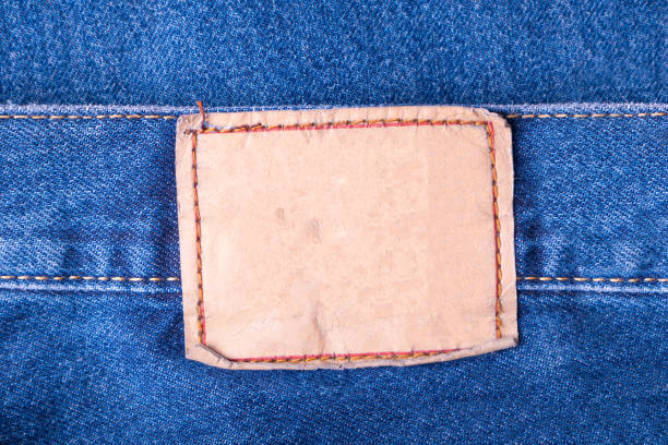 primo piano di etichetta in pelle macchiata bianca su blue jeans - leather patch denim jeans foto e immagini stock