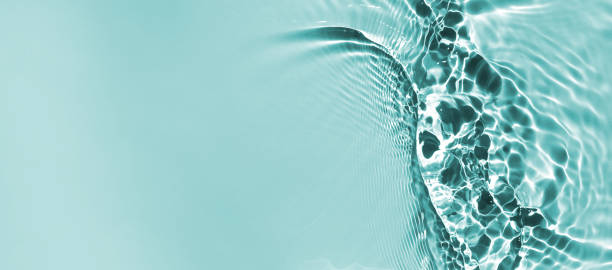 istock Trendy summer nature banner.  Defocused aqua-mint liquid colored clear water surface texture with splashes bubbles with copy space. Water waves in sunlight background. 1329845139