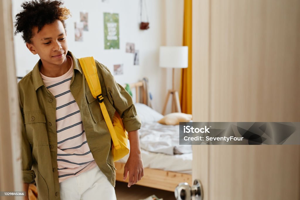 Boy Leaving for School Waist up portrait of mixed-race teenage boy holding backpack and opening door while leaving for school in morning, copy space Teenage Boys Stock Photo