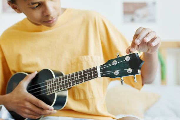 teenage boy spielt ukulele - uke stock-fotos und bilder