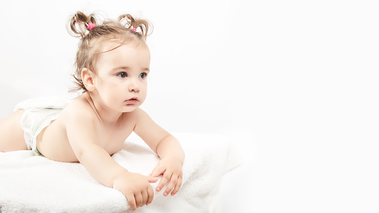 The little one-year-old girl lies on the bed a white background.. Concept of Health and Medicine. copy space